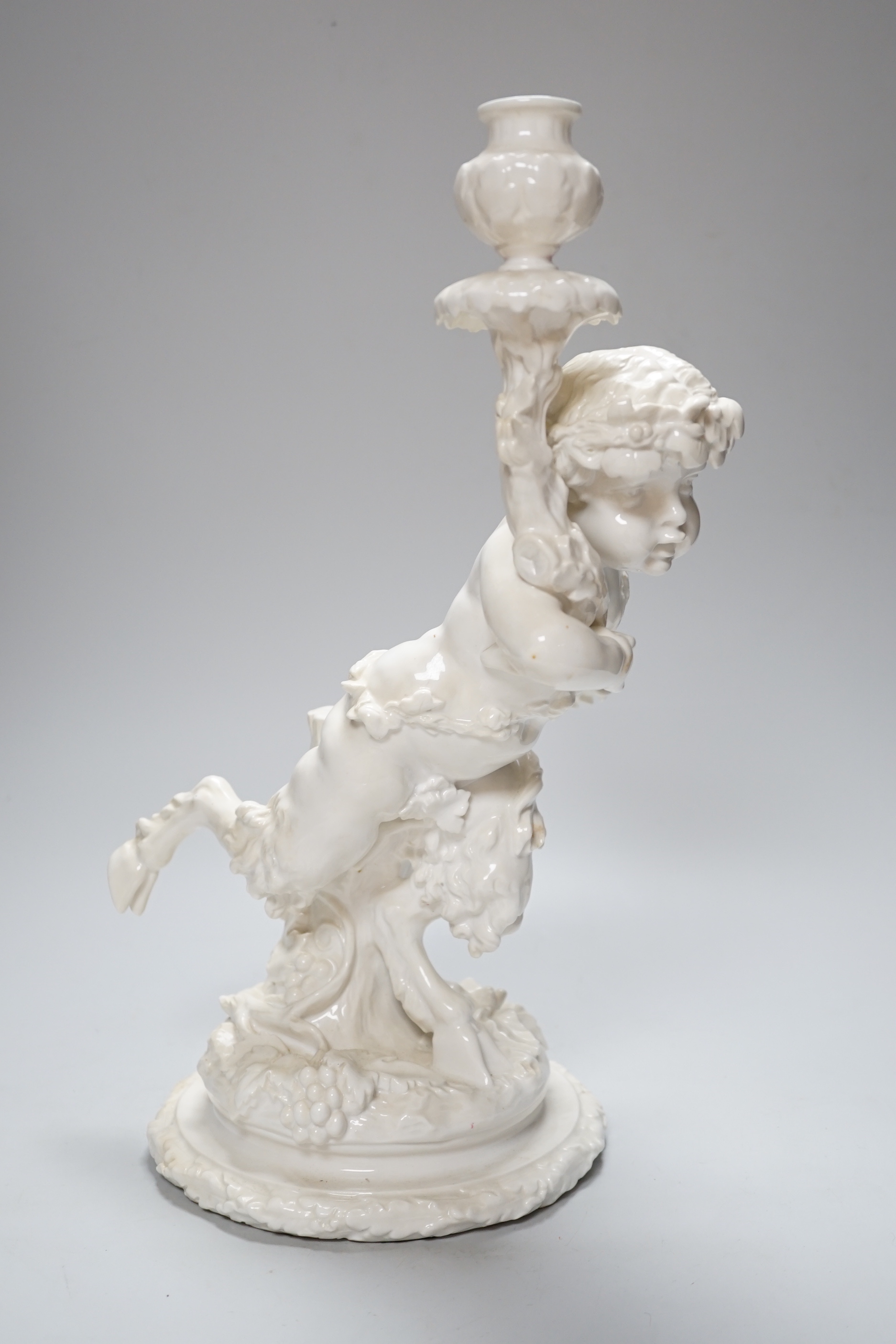 An English white glazed porcelain Bacchanalian fawn candlestick, possibly Moore Brothers, 39cm high